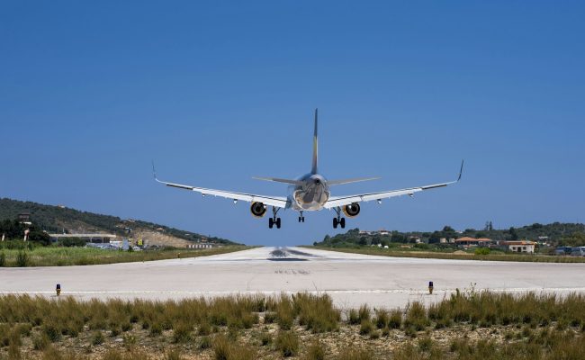 Closeup shot of a plane landing in a small airport with houses and forests on the background